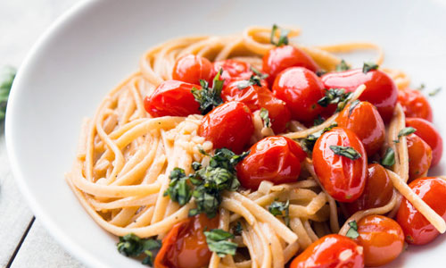 A freshly tossed plate of Garlic Tomato Linguine in a deep ceramic bowl.