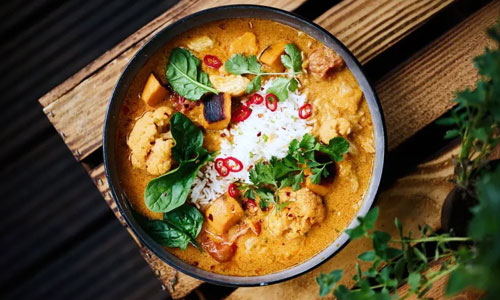 Rich green Thai Curry served in a traditional rustic clay pot.