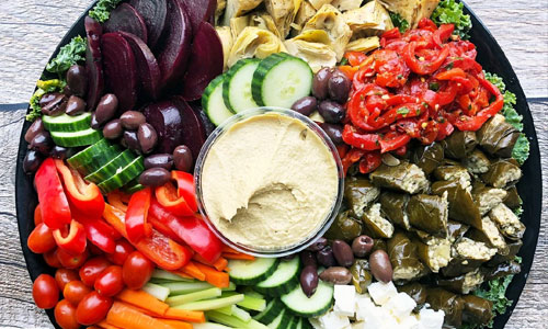 A generous Mediterranean plate featuring falafel, fresh salads, and hummus spreads.